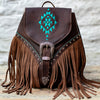 Brown leather backpack with turquoise geometric design and fringes on a wooden surface.