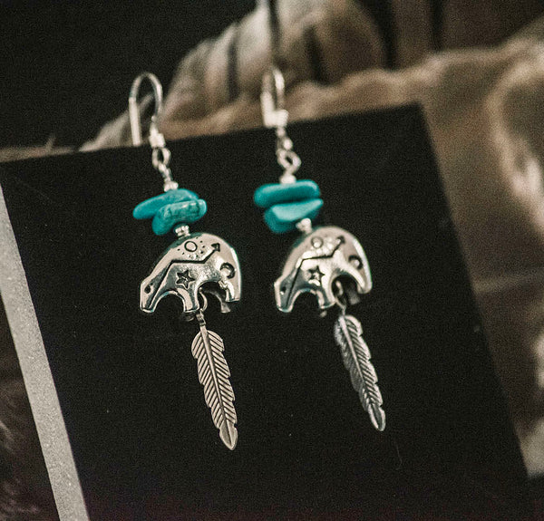 A super cute bear design hanging earrings with chunks of genuine turquoise nuggets and feather detailing for those that love a piece with spiritual significance.  The delicate bear pendant is engraved with tiny tribal motifs. Authentic handmade Native American Jewelry. 