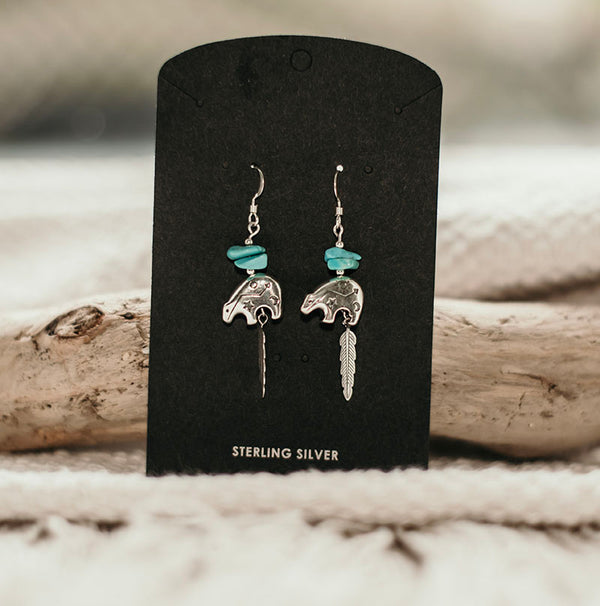 A super cute bear design hanging earrings with chunks of genuine turquoise nuggets and feather detailing for those that love a piece with spiritual significance. The delicate bear pendant is engraved with tiny tribal motifs. Authentic handmade Native American Jewelry.