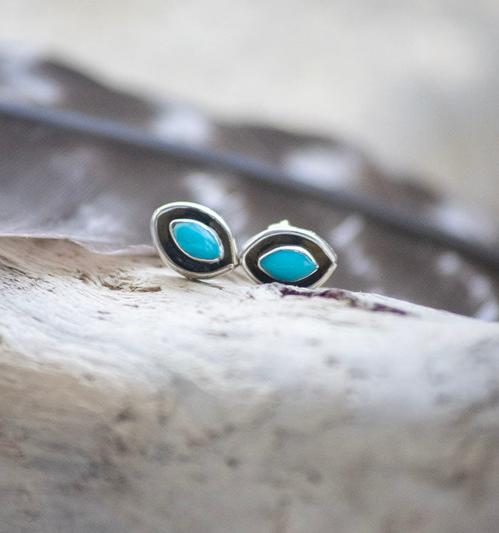 Southwestern silver and Turquoise stud earrings. This picture shows one of the two available styles: circular silver with a diamond piece of turquoise displayed on a black background A These studs are handmade authentic Native American jewelry. 